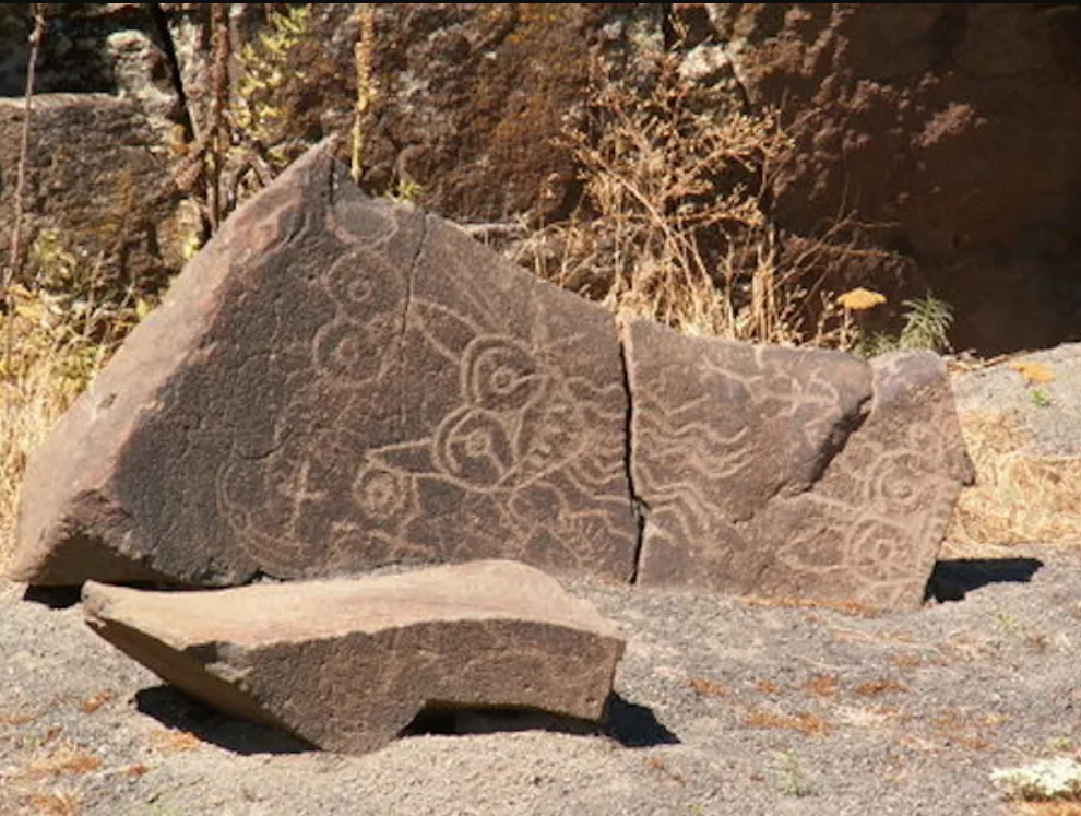 Picture of ancient Native American rock art. The depiction of a creation appears as lighter lines on a darker, cracked apart rock.